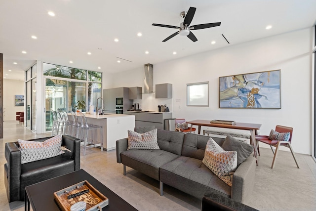 living room with expansive windows, ceiling fan, and sink