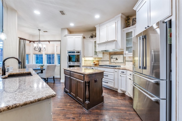 kitchen with pendant lighting, sink, white cabinetry, a center island, and stainless steel appliances