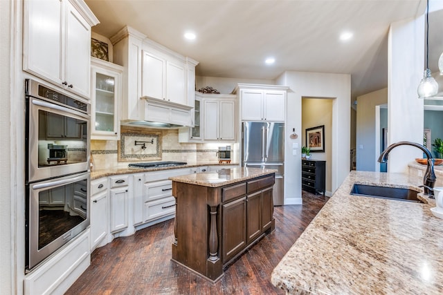 kitchen with white cabinets, decorative light fixtures, stainless steel appliances, decorative backsplash, and sink