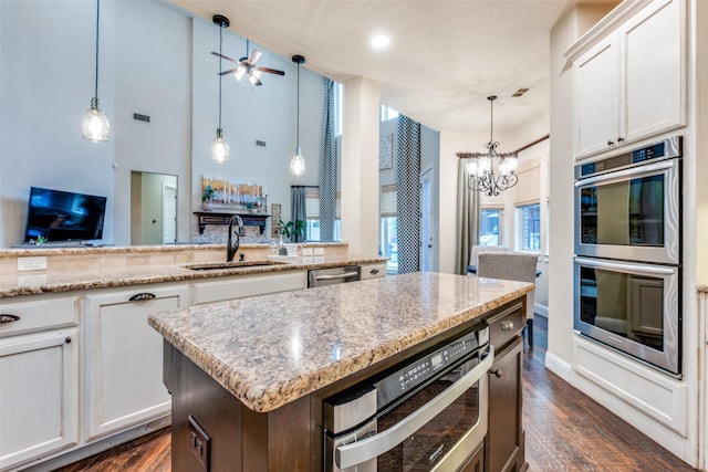 kitchen featuring sink, stainless steel appliances, white cabinetry, and pendant lighting