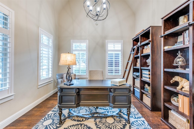 office area with dark hardwood / wood-style floors, high vaulted ceiling, and a notable chandelier