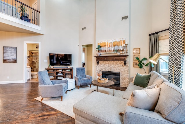 living room with dark hardwood / wood-style floors, a towering ceiling, and a fireplace