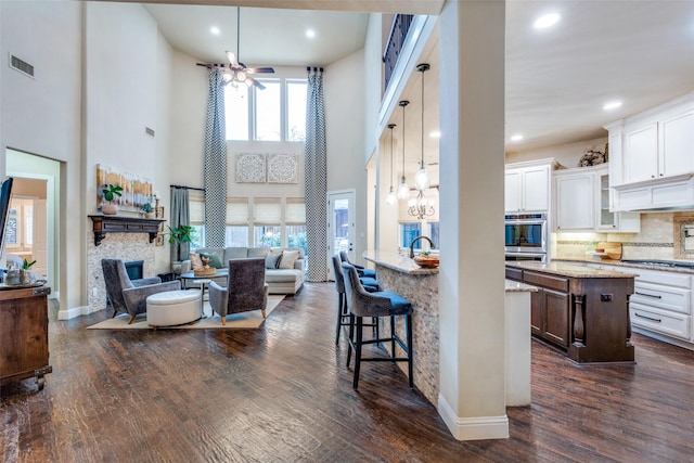 kitchen featuring white cabinets, a center island, a high ceiling, and light stone counters