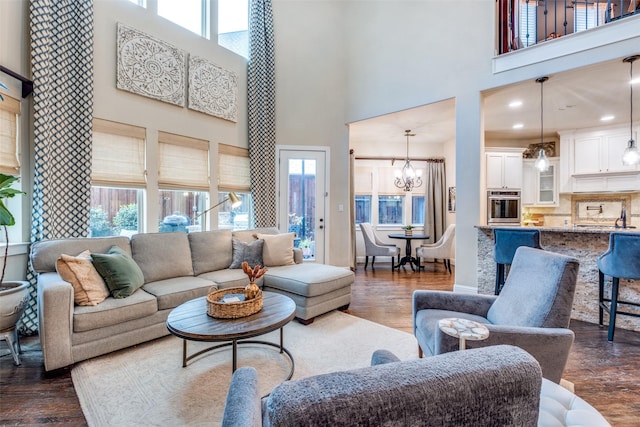 living room with an inviting chandelier, a towering ceiling, and a wealth of natural light