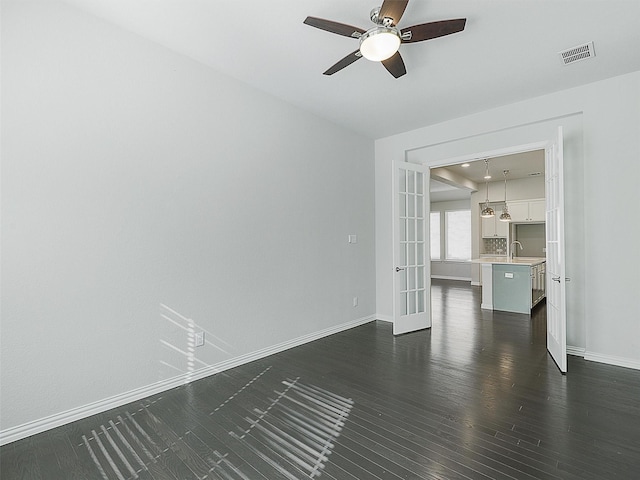 unfurnished living room with sink, dark wood-type flooring, ceiling fan, and french doors