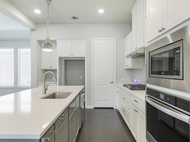 kitchen with sink, white cabinets, hanging light fixtures, and appliances with stainless steel finishes