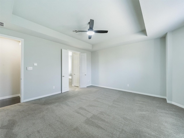 empty room with ceiling fan, a raised ceiling, and light colored carpet