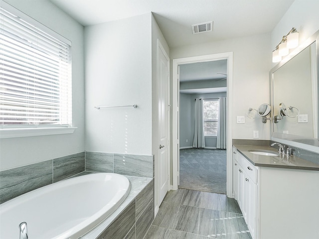 bathroom with tiled tub and vanity