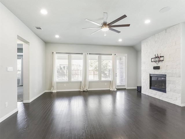 unfurnished living room with ceiling fan, a stone fireplace, and dark hardwood / wood-style flooring