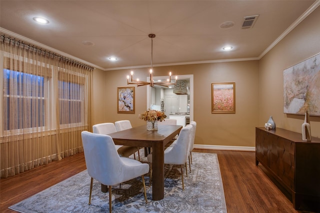 dining room featuring dark hardwood / wood-style floors, ornamental molding, and a notable chandelier