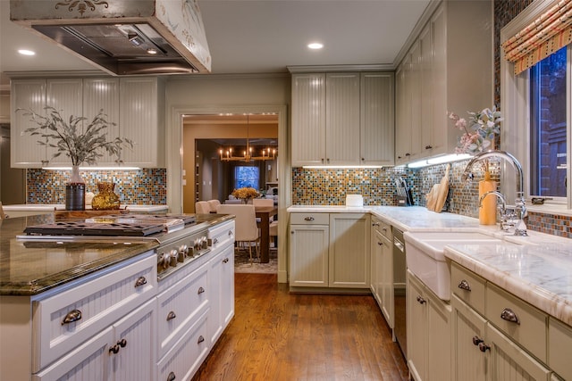 kitchen with custom exhaust hood, sink, light hardwood / wood-style flooring, an inviting chandelier, and backsplash