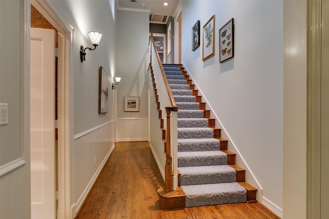 staircase with hardwood / wood-style floors and ornamental molding