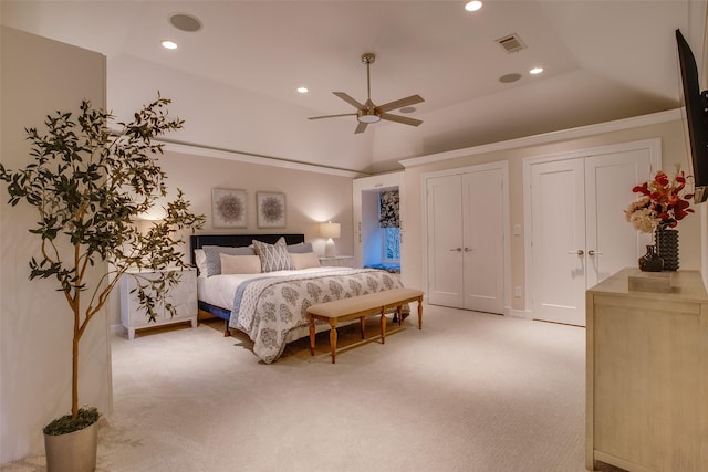 carpeted bedroom featuring two closets, vaulted ceiling, and ceiling fan