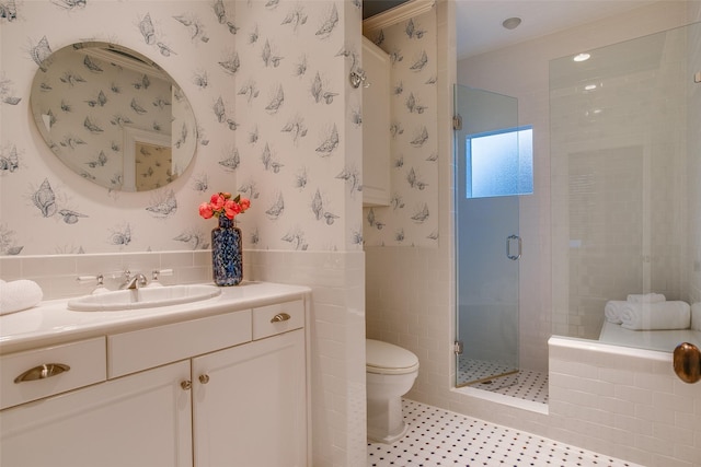 bathroom with a shower with shower door, toilet, tile walls, tile patterned floors, and vanity