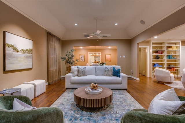 living room featuring lofted ceiling, ceiling fan, built in features, hardwood / wood-style flooring, and crown molding