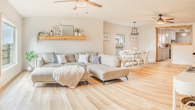 living room featuring ceiling fan, sink, ornamental molding, and light wood-type flooring