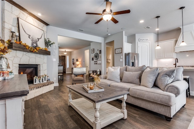 living room with ceiling fan, sink, dark hardwood / wood-style floors, and a fireplace