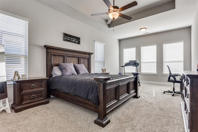 carpeted bedroom with a tray ceiling and ceiling fan