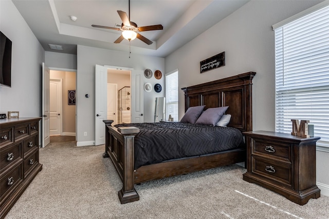 bedroom featuring connected bathroom, ceiling fan, a raised ceiling, and light colored carpet