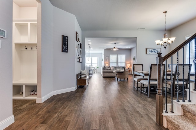 interior space featuring ceiling fan with notable chandelier and dark hardwood / wood-style flooring