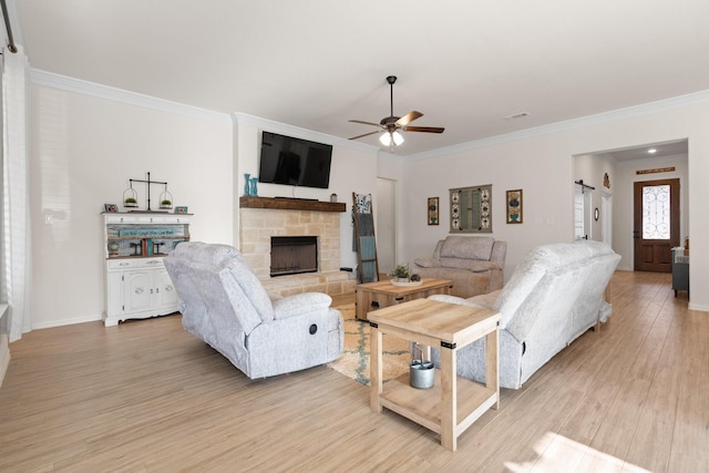 living room featuring light wood-type flooring, ceiling fan, ornamental molding, and a fireplace