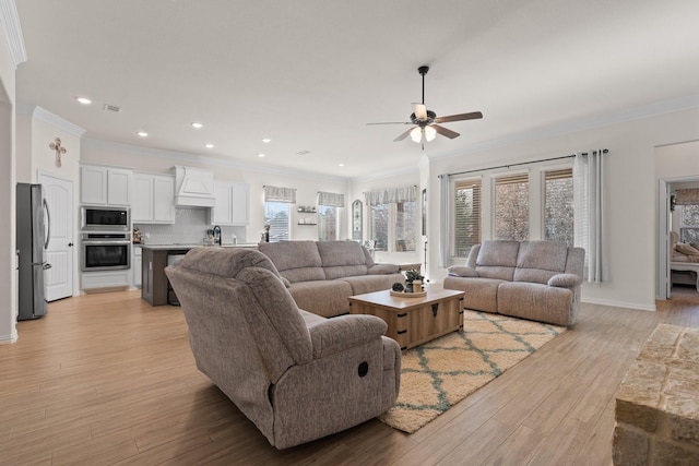 living room featuring ceiling fan, sink, light hardwood / wood-style flooring, and ornamental molding