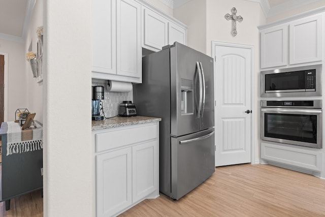 kitchen featuring stainless steel appliances, white cabinetry, crown molding, and backsplash