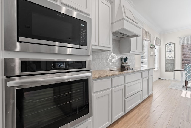 kitchen with built in microwave, black electric cooktop, white cabinets, and oven