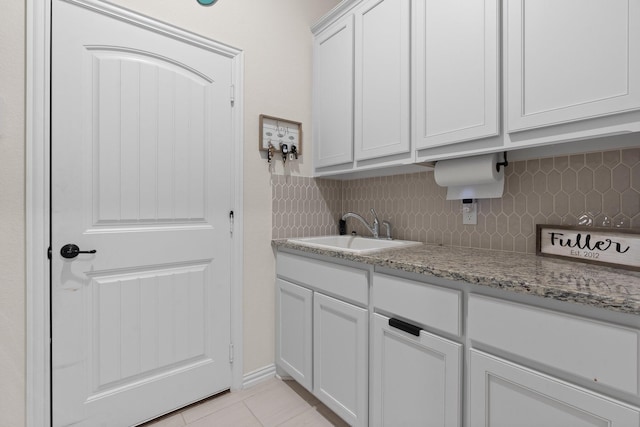 laundry area featuring sink and light tile patterned flooring