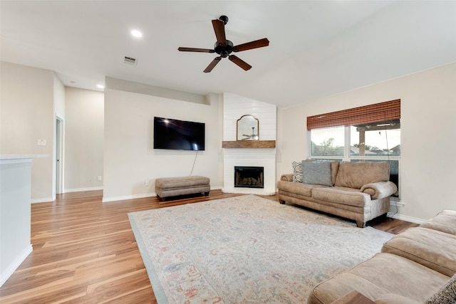 living room with ceiling fan, a fireplace, and light hardwood / wood-style floors