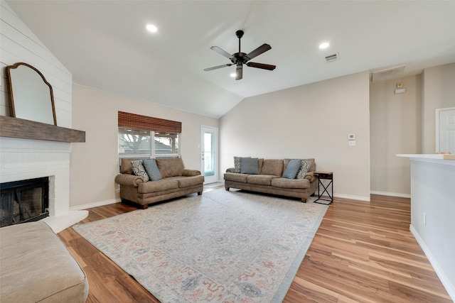 living room featuring ceiling fan, a fireplace, vaulted ceiling, and hardwood / wood-style floors