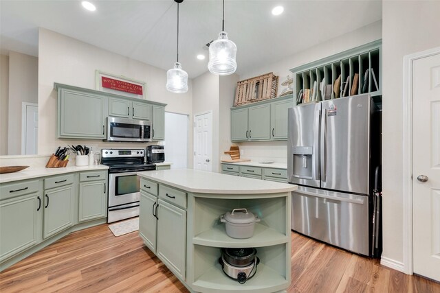 kitchen with green cabinets, appliances with stainless steel finishes, a kitchen island, decorative light fixtures, and light wood-type flooring