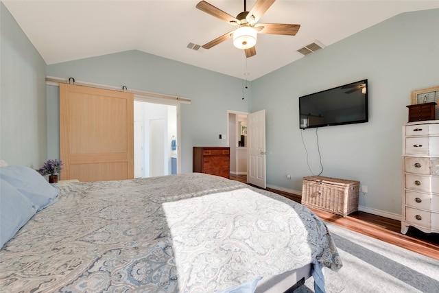 bedroom with hardwood / wood-style flooring, ceiling fan, lofted ceiling, and a barn door