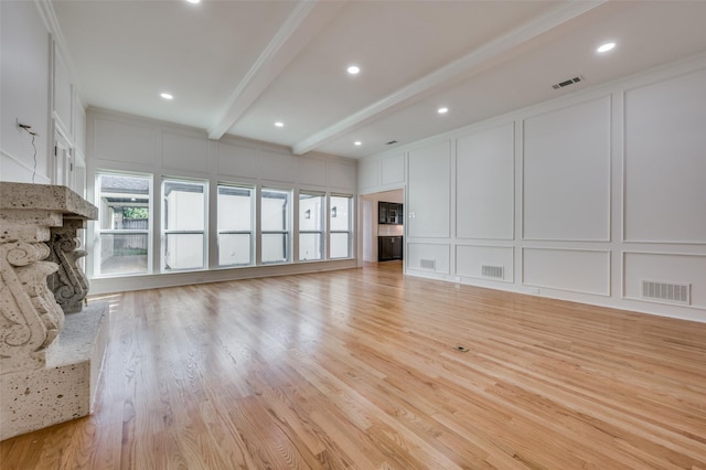 unfurnished living room featuring light hardwood / wood-style floors, beamed ceiling, and ornamental molding