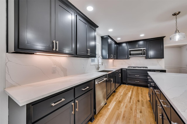 kitchen featuring light hardwood / wood-style flooring, decorative light fixtures, sink, tasteful backsplash, and stainless steel appliances