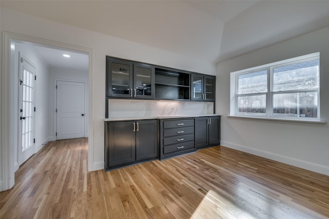 bar with a wealth of natural light, light hardwood / wood-style flooring, decorative backsplash, and lofted ceiling