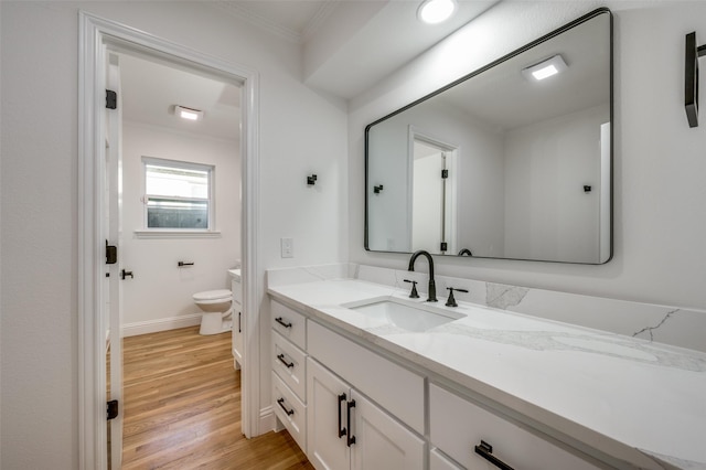 bathroom featuring hardwood / wood-style floors, toilet, vanity, and ornamental molding