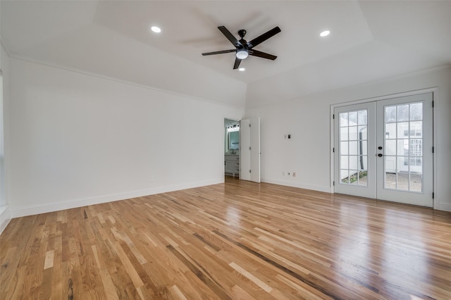 unfurnished room with light wood-type flooring, vaulted ceiling, french doors, and a tray ceiling