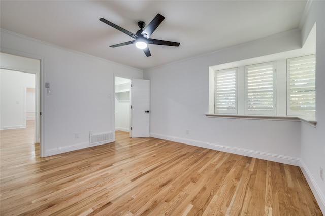 unfurnished bedroom with light hardwood / wood-style floors, a spacious closet, ceiling fan, and ornamental molding