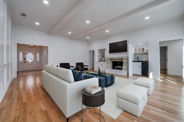 living room with built in shelves, light hardwood / wood-style floors, beamed ceiling, and sink