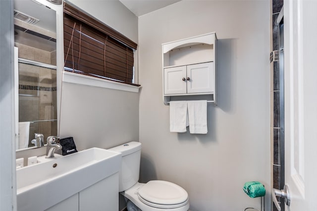 bathroom with a shower with shower door, sink, and toilet