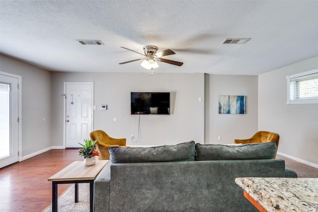 living room with ceiling fan, dark wood-type flooring, and a textured ceiling