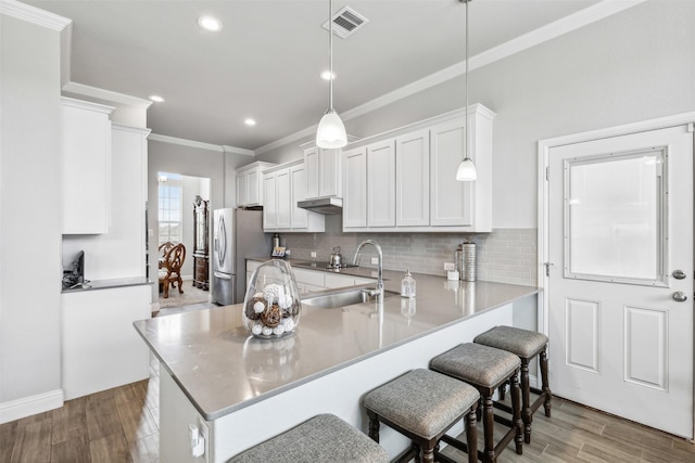 kitchen with white cabinetry, stainless steel refrigerator with ice dispenser, sink, decorative light fixtures, and kitchen peninsula