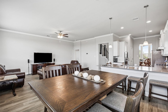 dining area featuring sink, ceiling fan, light hardwood / wood-style flooring, and crown molding