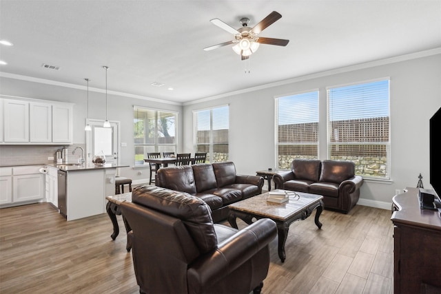 living room featuring crown molding, sink, light hardwood / wood-style flooring, and ceiling fan