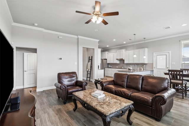 living room featuring light wood-type flooring, ceiling fan, and crown molding