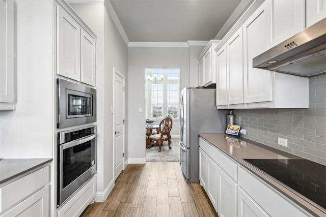 kitchen featuring tasteful backsplash, a chandelier, white cabinetry, ornamental molding, and stainless steel appliances