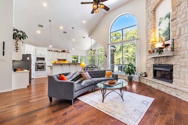 living room with visible vents, dark wood finished floors, a wealth of natural light, and a stone fireplace