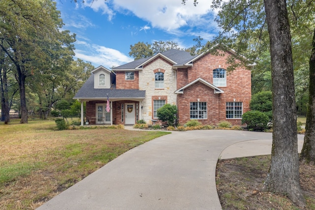 traditional-style house featuring stone siding, brick siding, and a front yard