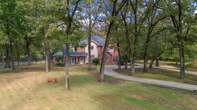 view of front facade with driveway, a front lawn, and brick siding